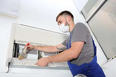 technician cleaning air conditioner indoors