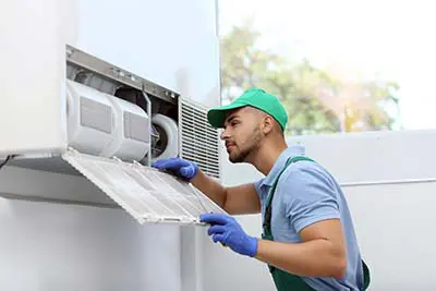 Professional technician maintaining modern air conditioner indoors